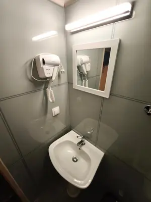 a bathroom with a sink and a mirror and a hair dryer at Liberal Mini Rooms in Athens