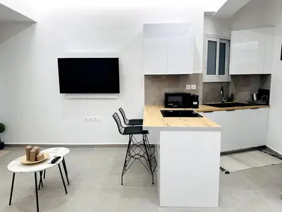 a kitchen with white cabinets and a table and chairs at Central Apartment At Pangrati in Athens