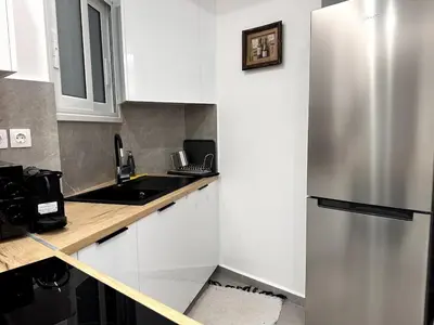 a kitchen with white cabinets and a stainless steel refrigerator at Central Apartment At Pangrati in Athens