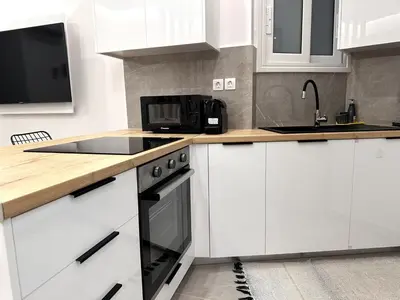 a kitchen with white cabinets and a black microwave at Central Apartment At Pangrati in Athens