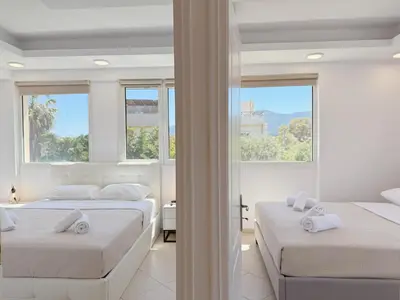 two beds in a white room with windows at Beachfront 3bedroom apartment in Porto Rafti