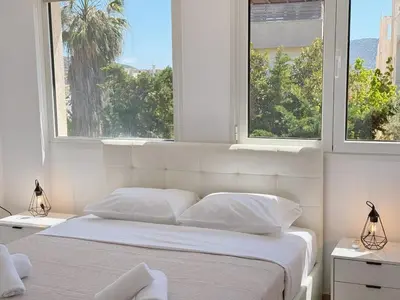 a bedroom with a large white bed with two windows at Beachfront 3bedroom apartment in Porto Rafti