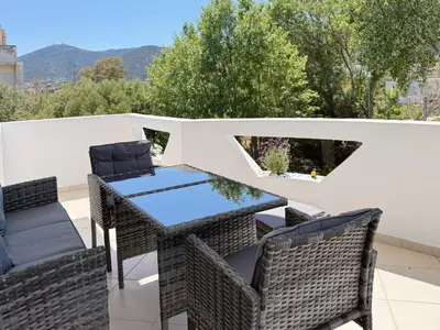 a patio with wicker chairs and a table on a balcony at Beachfront 3bedroom apartment in Porto Rafti