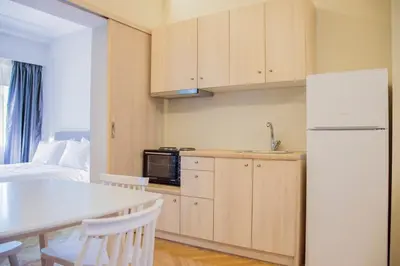 a kitchen with a refrigerator and a table with chairs at Athens Luxury Apartments Lindos in Athens