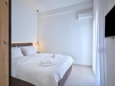 a bedroom with a bed with white sheets and a mirror at CorNeliApartment in Athens