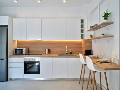 a kitchen with white cabinets and a table with chairs at CorNeliApartment in Athens