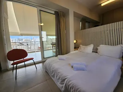 a bedroom with a large bed with a chair and a window at Skynest Studio byYHA in Athens