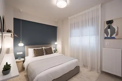 a bedroom with a large bed and a blue wall at Aminandrou Boutique Apartments, Walk to Acropolis in Athens