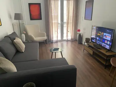 a living room with a couch and a flat screen tv at Cozy & Connected, Walk to Culture, Metro in Minutes in Athens