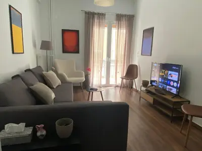 a living room with a couch and a flat screen tv at Cozy & Connected, Walk to Culture, Metro in Minutes in Athens