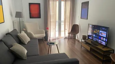 a living room with a couch and a flat screen tv at Cozy & Connected, Walk to Culture, Metro in Minutes in Athens