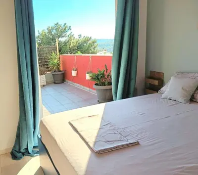 a bedroom with a bed and a balcony with plants at Vouliagmeni Top Floor Maisonette in Athens