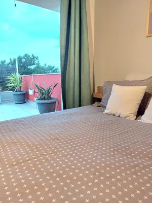 a bedroom with a bed and a balcony with plants at Vouliagmeni Top Floor Maisonette in Athens