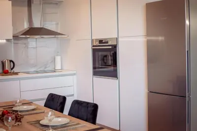 a kitchen with a table and a stainless steel refrigerator at Voula Hill Panoramic Views of Sea and Athens 129 sqm 2 bedrooms 2 bathrooms Big Fully Equipped New Apartment Peaceful in Athens