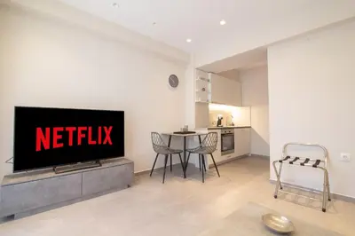 a living room with a television and a table with chairs at Nafsika Cozy Flat A - Glyfada in Athens