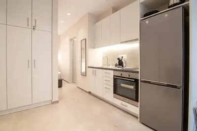 a kitchen with white cabinets and a stainless steel refrigerator at Nafsika Cozy Flat A - Glyfada in Athens