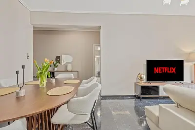 a living room with a table and chairs and a tv at 3BD Luxury Apartment close to Metro in Athens