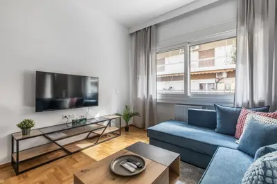 a living room with a blue couch and a tv at Cozyopolis - Timeless 3-BR Escape in Athens in Athens