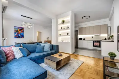a living room with a blue couch and a table at Cozyopolis - Timeless 3-BR Escape in Athens in Athens