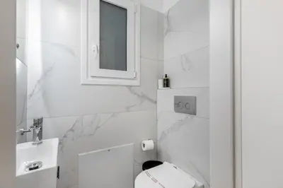 a white bathroom with a toilet and a sink at Cozyopolis - Timeless 3-BR Escape in Athens in Athens