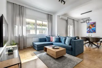 a living room with a blue couch and a table at Cozyopolis - Timeless 3-BR Escape in Athens in Athens