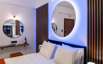 a bedroom with a white bed and two mirrors at Dema Luxury Suites - Romvis in Athens
