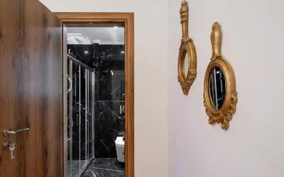 a bathroom with a toilet and a mirror on the door at Dema Luxury Suites - Romvis in Athens
