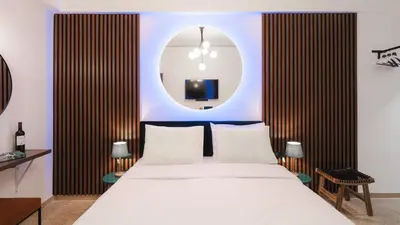 a bedroom with a white bed and a round mirror at Dema Luxury Suites - Romvis in Athens