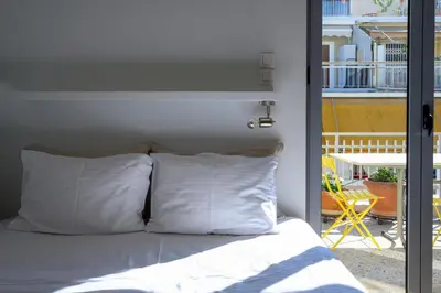 a bed with white pillows in front of a balcony at Sunbathed Balcony - Philopappou View in Athens