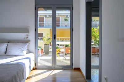 a bedroom with a bed and sliding glass doors at Sunbathed Balcony - Philopappou View in Athens