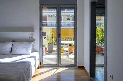 a bedroom with a bed and a sliding glass door at Sunbathed Balcony - Philopappou View in Athens