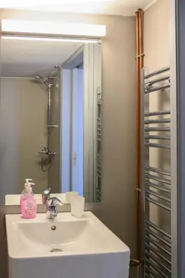 a bathroom with a white sink and a mirror at Sunbathed Balcony - Philopappou View in Athens