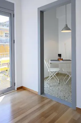 an open door into a white room with a table at Sunbathed Balcony - Philopappou View in Athens