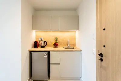 a small kitchen with white cabinets and a sink at Grec Suites Dafni, Athens by GrecCollection in Athens