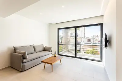 a living room with a couch and a large window at Grec Suites Dafni, Athens by GrecCollection in Athens