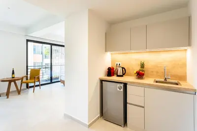 a kitchen with white cabinets and a table and chairs at Grec Suites Dafni, Athens by GrecCollection in Athens