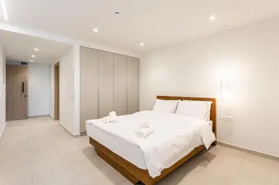 a white bedroom with a large bed with white sheets at Grec Suites Dafni, Athens by GrecCollection in Athens