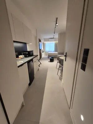 a kitchen with white cabinets and a long hallway at Shape Suites Athens in Athens