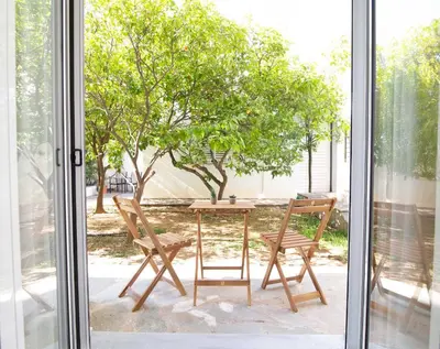a table and two chairs on a patio with a tree at Nafsika Cozy Flat B - Glyfada in Athens