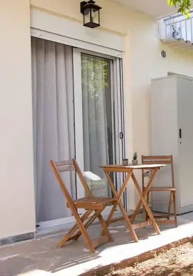 a table and two chairs sitting next to a glass door at Nafsika Cozy Flat B - Glyfada in Athens
