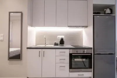 a kitchen with white cabinets and a sink and a refrigerator at Nafsika Cozy Flat B - Glyfada in Athens