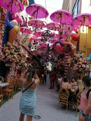 a woman standing in front of a market with pink umbrellas at ACROPOLI AND MONASTIRAKI HOMe1 in Athens