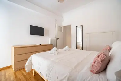 a white bedroom with a white bed and a television at Casa di Anna 1 bed 4 pers Apt by MPS in Athens