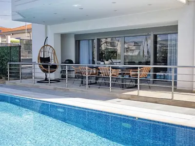 a patio with a table and chairs next to a swimming pool at Costa Voula Poolside and Beach, Home Cinema in Athens