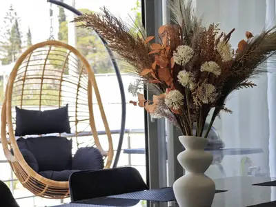 a vase with flowers on a table next to a chair at Costa Voula Poolside and Beach, Home Cinema in Athens