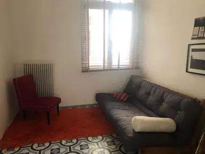 a living room with a black couch and a red chair at Heritage house in Athens' heart in Athens