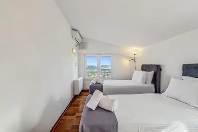 two beds in a room with a window at Sea View Residence Panorama Villa in Saronida