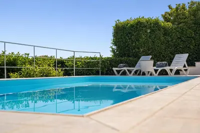 a swimming pool in a villa with chairs and trees at Sea View Residence Panorama Villa in Saronida