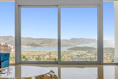 a room with three windows and a table and chairs at Sea View Residence Panorama Villa in Saronida