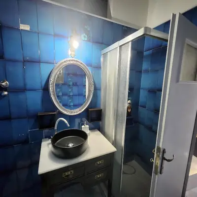 a blue tiled bathroom with a sink and a mirror at Athens King 1 in Athens